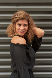 Portrait of smiling young woman standing against wall