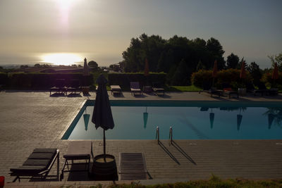 Swimming pool by sea against sky during sunset