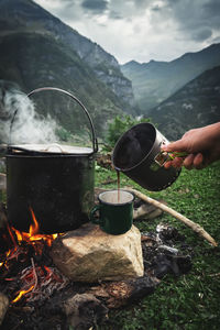 Coffee is poured from a pot into a cup in the morning on a hike in the caucasus mountains
