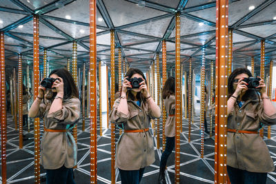 Young woman with camera in mirror maze