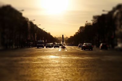 Cars on road in city against sky during sunset