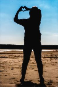 Silhouette woman standing at beach against sky