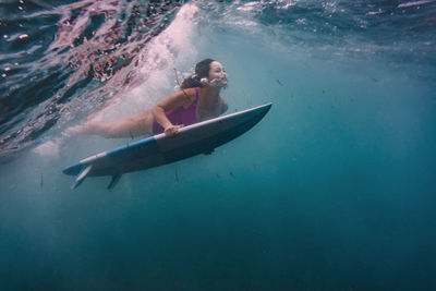 Female surfing on surfboard underwater