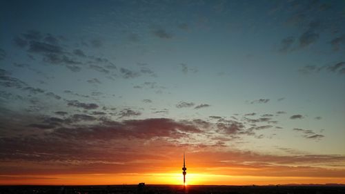 Silhouette electricity pylon against dramatic sky during sunset