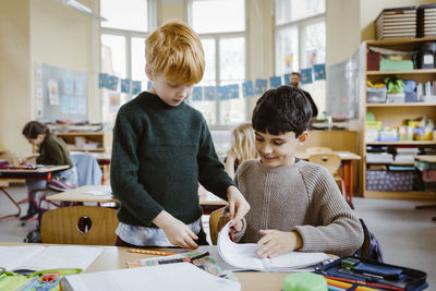 Boys sharing book while learning in classroom