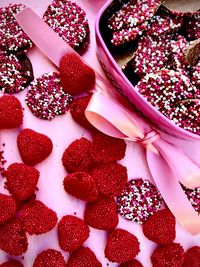 Red jelly candy hearts and pink ribbon bow along side tin heart shaped box