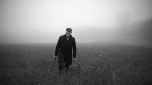 Woman standing on field in foggy weather