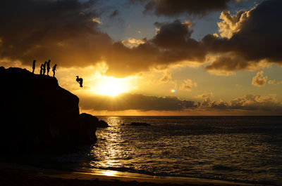 Silhouette man on beach against sky during sunset