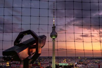 Fernsehturm seen through netting during sunset