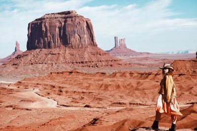 Side view of woman walking at desert against sky