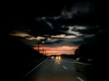 Cars on road against cloudy sky