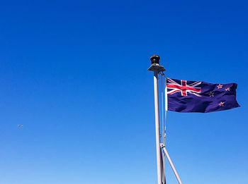 Low angle view of flag against clear blue sky