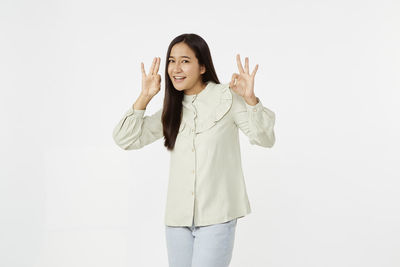 Portrait of smiling young woman standing against white background