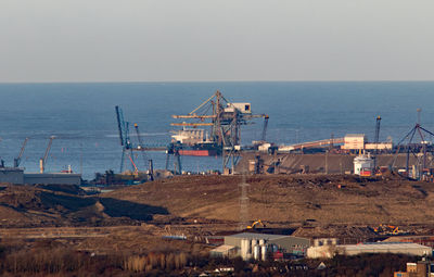 Commercial dock by sea against clear sky