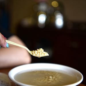 Cropped hand holding spoon over food bowl at home