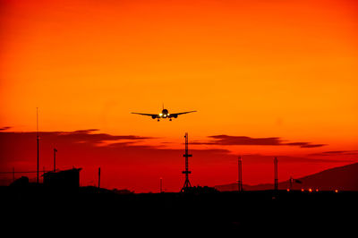 Low angle view of silhouette airplane against sky during sunset