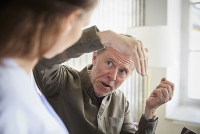 Mature male professional explaining to female colleague at board room