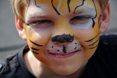 Close-up portrait of boy with tiger face painting