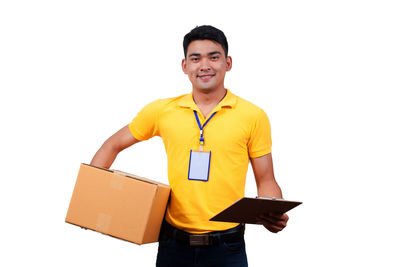 Portrait of smiling delivery man with cardboard box and clipboard against white background