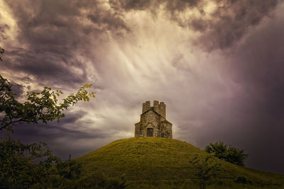 Castle on mountain against cloudy sky