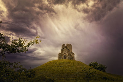 Low angle view of castle on hill against cloudy sky