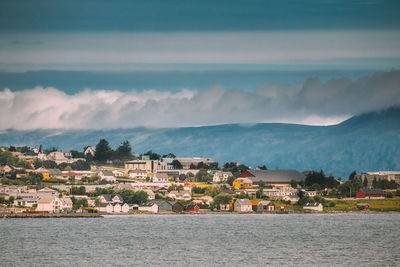 Buildings by sea against sky