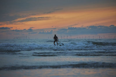 Full length of woman standing at beach against sky during sunset