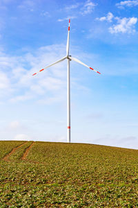 Windmills on field against sky and wind turbine