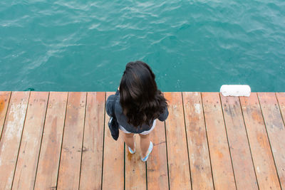 High angle view of woman standing on pier in sea