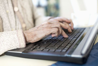 Midsection of senior woman using laptop at home
