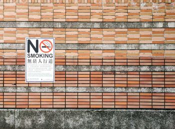 Close-up of no smoking sign on brick wall