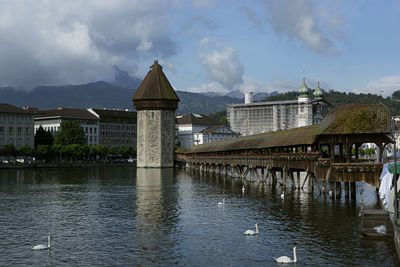 Kapellbrucke bridge over river by buildings against cloudy sky