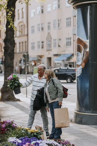 Male and female senior friends buying plant from nursery at street