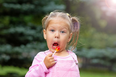 Beautiful child with funny face licking lollipop