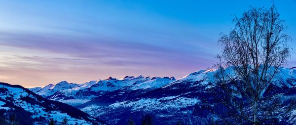 Scenic view of snowcapped mountains against blue sky during sunset