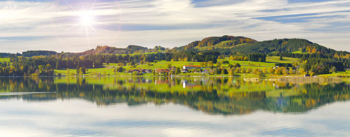 Wide angle view to alps mountain range mirroring in lake forggensee in region allgaeu in bavaria