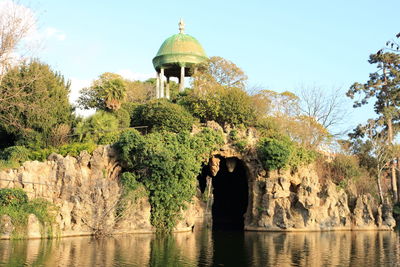 Low angle view of rock formation by lake against sky