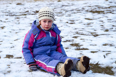 Portrait of man sitting on snow covered field