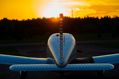 Airplane on tree by lake against sky during sunset