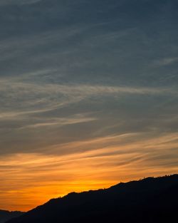 Scenic view of silhouette mountains against orange sky