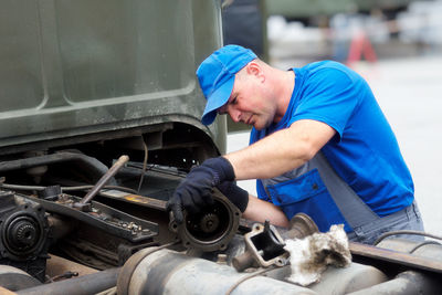 Side view of man repairing car