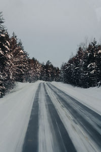 Road amidst trees against clear sky
