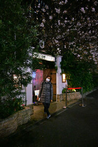 Side view of woman standing by plants against trees