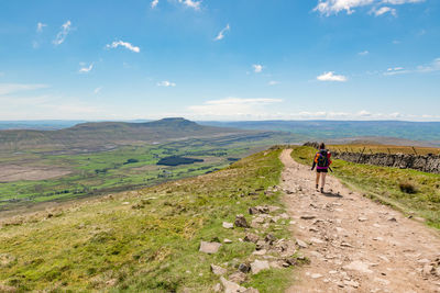 Rear view of men walking on land against sky