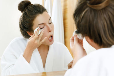 Woman removing make-up in bathroom