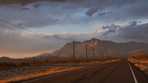 Road leading towards mountains against sky