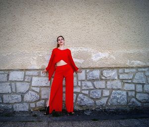 Portrait of woman standing against red wall