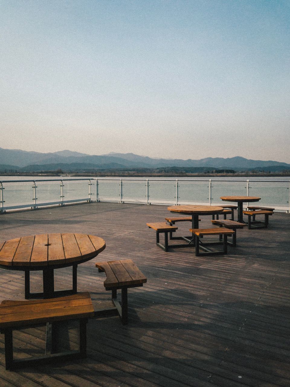 EMPTY CHAIRS AND TABLE AGAINST SEA