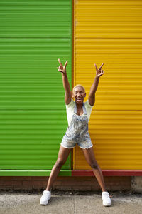 Portrait of a smiling girl standing against yellow wall