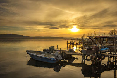 Boats moored in sea against sky during sunset